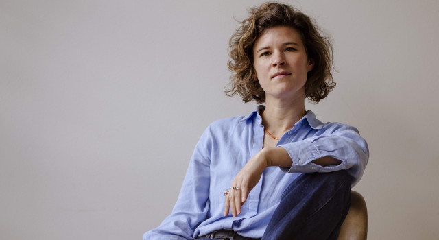 Daan Borrel zit op een stoel. Ze heeft geen schoenen of sokken aan.