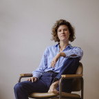 Daan Borrel zit op een stoel. Ze heeft geen schoenen of sokken aan.