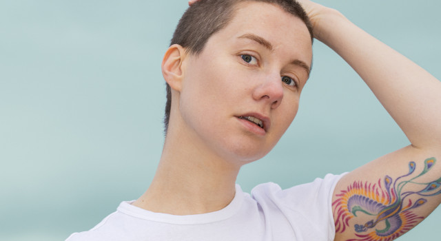 Valentijn Hoogenkamp, buiten, met bomen en struiken op de achtergond. Zijn haar is gemillimeterd. Op zijn arm een tattoo van een feniks.