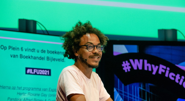 raoul de jong, auteur van het boekenweekessay, draagt een bril en een lichtroze tshirt, hij zit op het ilfu exploring stories