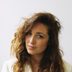 Foto van auteur Malou Holshuijsen. De draagt een witte colbert en glimlacht.