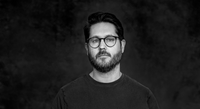 Gijs Wilbrink staat met zijn handen in zijn zakken. Onder de mouw van zijn T-shirt piept een tatoeage van de punkband Hot Water Music