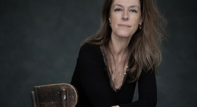 Mirjam van Hengel zit op een houten stoel, ze kijkt recht naar de camera