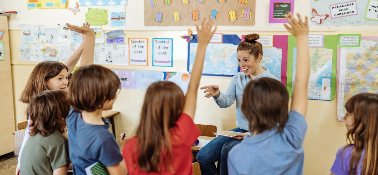 Foto van 6 schoolkinderen en een juf in een klaslokaal