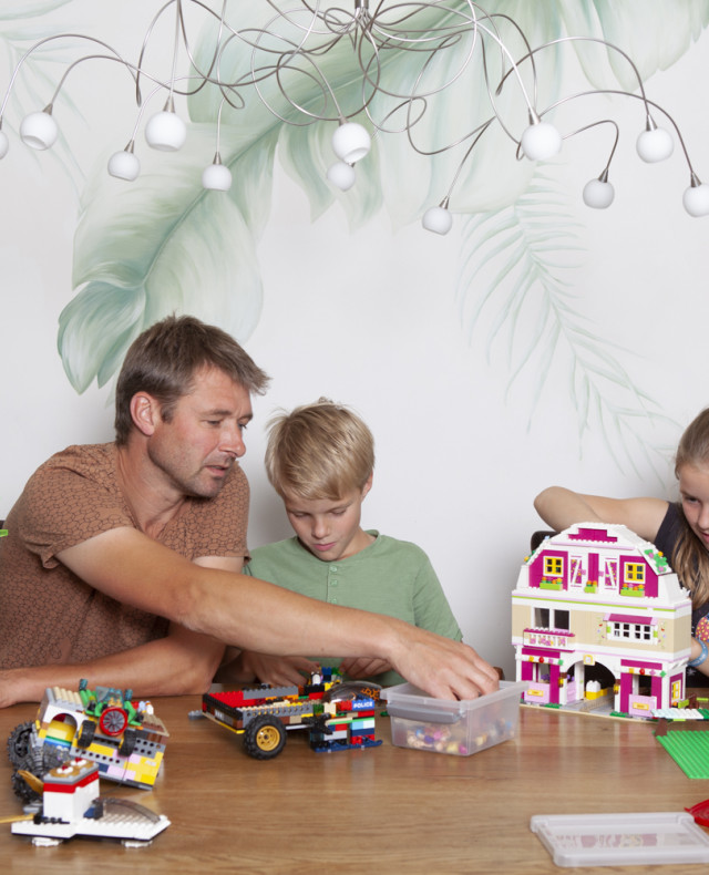 Foto van vader met 2 kinderen die met Lego spelen